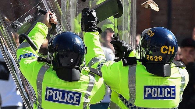 Les policiers se protègent des briques lancées par les manifestants lors de la protestation "Ça suffit", à Liverpool, le 3 août 2024. 