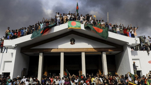 Des manifestants anti-gouvernementaux arborent le drapeau national du Bangladesh alors qu'ils prennent d'assaut le palais de la Première ministre Sheikh Hasina à Dhaka, le 5 août 2024.