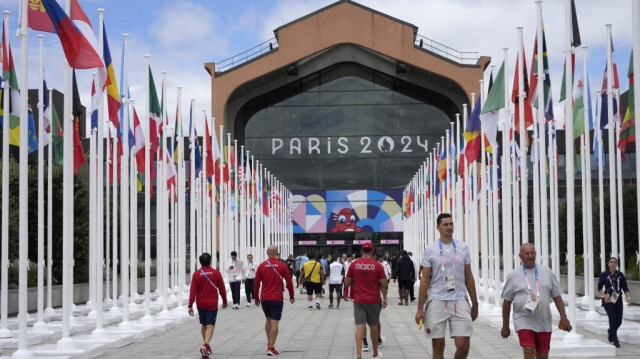 Les participants des Jeux olympiques et paralympiques de Paris 2024 marchent devant la cafétéria du village olympique, le 22 juillet 2024.