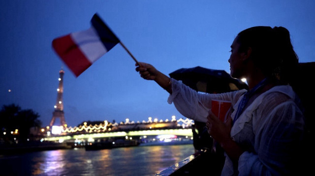 Une spectatrice agite un drapeau de l'équipe de France, près de la Tour Eiffel, lors de la cérémonie d'ouverture des Jeux Olympiques Paris 2024, le 26 juillet 2024 à Paris, en France.