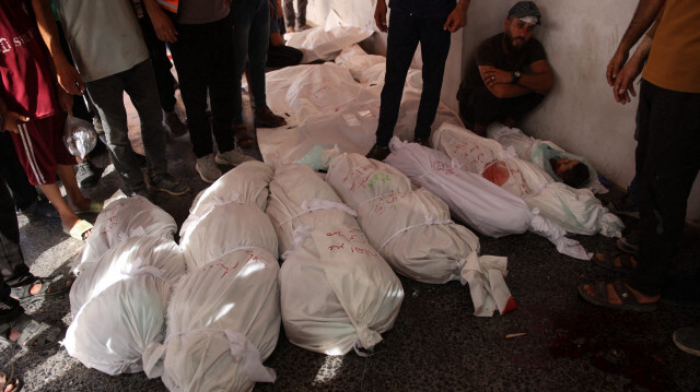 Des Palestiniens entourant des corps gisant sur le sol de l'hôpital al-Maamadani, après avoir été tués lors d'une frappe israélienne sur une école utilisée comme refuge par des Palestiniens déplacés dans la ville de Gaza, le 8 août 2024, dans le cadre du conflit en cours entre Israël et le groupe militant Hamas.