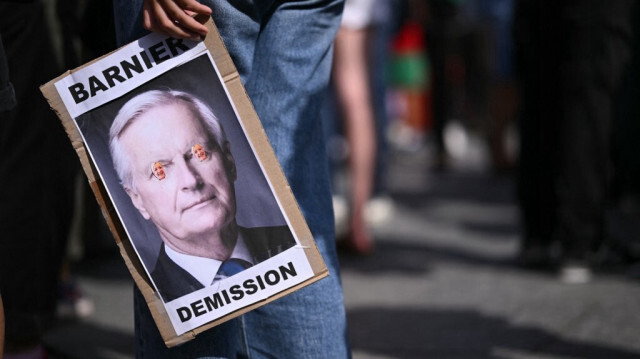 Un manifestant tient une pancarte avec une photo du Premier ministre Michel Barnier  lors d'une protestation contre sa nomination par le président français Emmanuel Macron à Strasbourg, dans l'est de la France, le 7 septembre 2024.