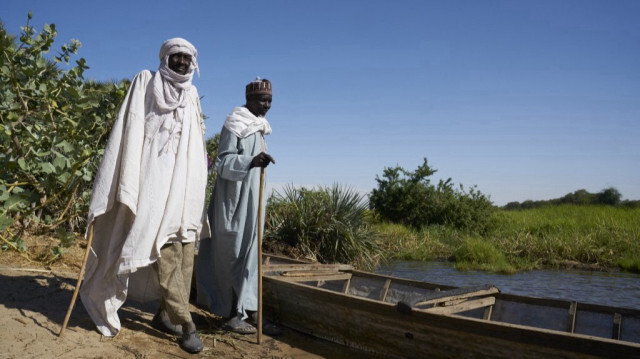 Des Tchadiens se tiennent près d'un bateau en bois sur les rives du lac Tchad, le 8 novembre 2018. 