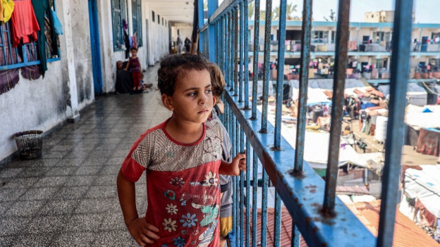 Des enfants palestiniens se tiennent derrière la balustrade d’un balcon, à l’extérieur des salles de classe d’une école abritant des civils déplacées par le conflit, gérée par l’UNRWA à Deir el-Balah, dans le centre de la bande de Gaza, le 9 septembre 2024.