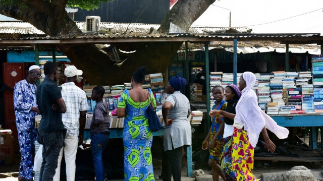 Des personnes se tiennent dans une librairie de bord de route vendant des livres et des magazines d'occasion à Abidjan, la plus grande ville de Côte d'Ivoire, le 19 septembre 2018.