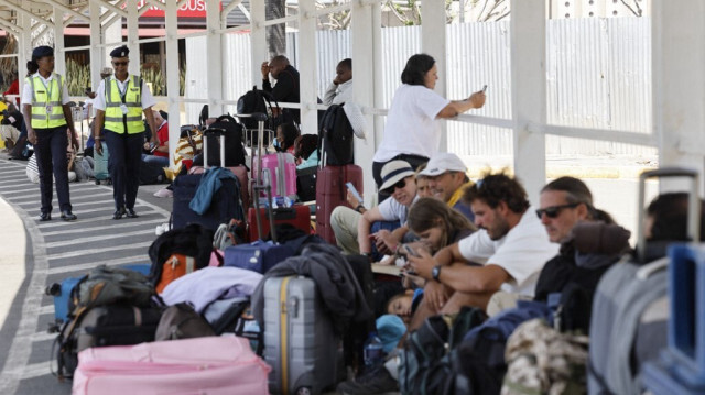 Des policiers kenyans passent devant des passagers qui attendent devant une porte fermée à l'aéroport international Jomo Kenyatta (JKIA) de Nairobi, le 11 septembre 2024, dans le cadre d'une grève du syndicat des travailleurs de l'aviation kenyans. 