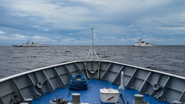 Les navires des garde-côtes chinois (à gauche et à droite) sont vus depuis le navire des garde-côtes philippins BRP Cabra lors d'une mission de ravitaillement sur le Sabina Shoal dans les eaux contestées de la mer de Chine méridionale, le 26 août 2024.