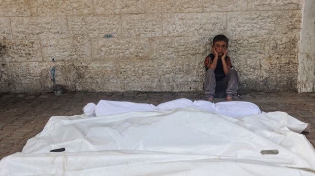 Un enfant palestinien désemparé, assis à côté des corps enveloppés de personnes tuées lors d'une frappe israélienne nocturne, dans la cour de l'hôpital des Martyrs d'Al-Aqsa à Deir el-Balah, dans le centre de la bande de Gaza, le 10 août 2024.