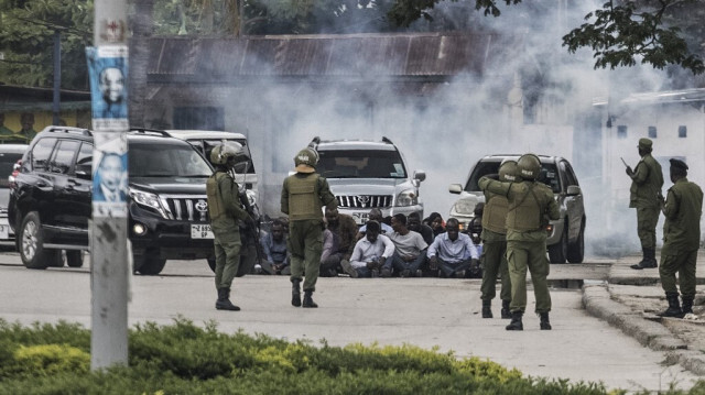 Des officiers de la police anti-émeute de Zanzibar surveillent un groupe d'hommes assis au sol lors d'une opération, suite à l'appel de l'opposition à manifester à Stone Town, le 29 octobre 2020, alors que les tensions montent avec l'annonce des résultats des élections générales.