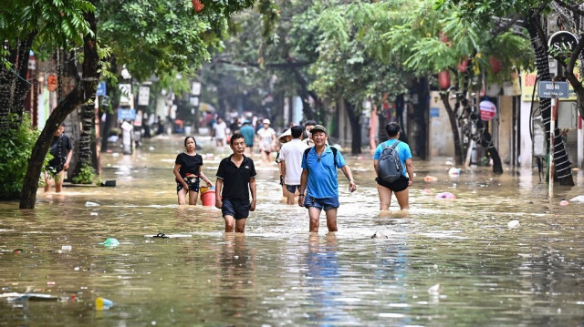 Des personnes pataugent dans les eaux de crue dans une rue de Hanoi le 12 septembre 2024, alors que les fortes pluies consécutives au typhon Yagi ont provoqué des inondations dans le nord du Viêt Nam.