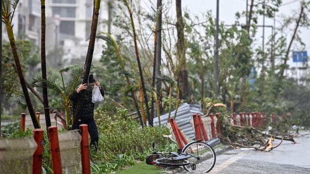 Une femme s'accroche à un tronc d'arbre alors qu'elle marche près d'une route inondée après le passage du super typhon Yagi à Hai Phong, le 7 septembre 2024. Le super typhon Yagi a déraciné des milliers d'arbres et balayé des navires et des bateaux en mer lorsqu'il a touché terre dans le nord du ViêtNam le 7 septembre, ont indiqué les médias d'État.