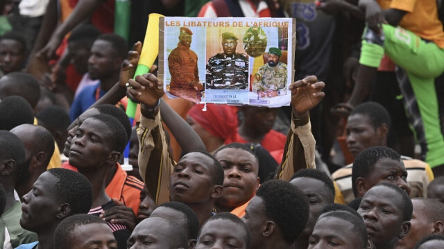 Un homme tient une pancarte à l'effigie du nouveau chef militaire du Niger, le général Abdourahamane Tiani, alors que des partisans du Conseil national de sauvegarde de la patrie (CNSP) manifestent devant la base aérienne nigéro-française de Niamey, le 2 septembre 2023, pour exiger le départ de l'armée française du Niger.