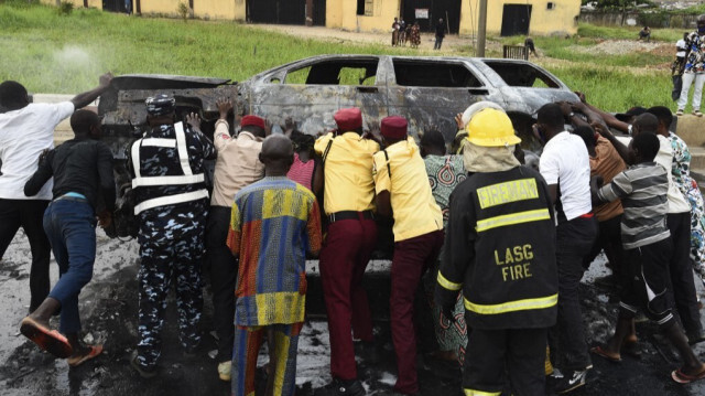 Des personnes tentent d'écarter une voiture brûlée bloquant la route afin de rétablir la circulation dans le district d'Alapere à Lagos, le 15 janvier 2021.
