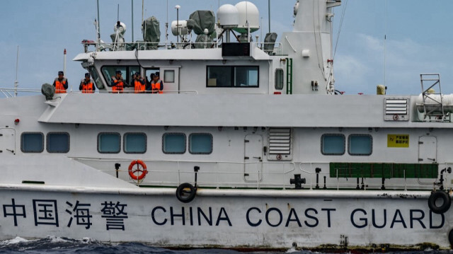 Des employés à bord d'un navire des garde-côtes chinois observés depuis le navire des garde-côtes philippins BRP Cabra lors d'une mission de ravitaillement au Sabina Shoal dans les eaux disputées de la mer de Chine méridionale, le 26 août 2024.