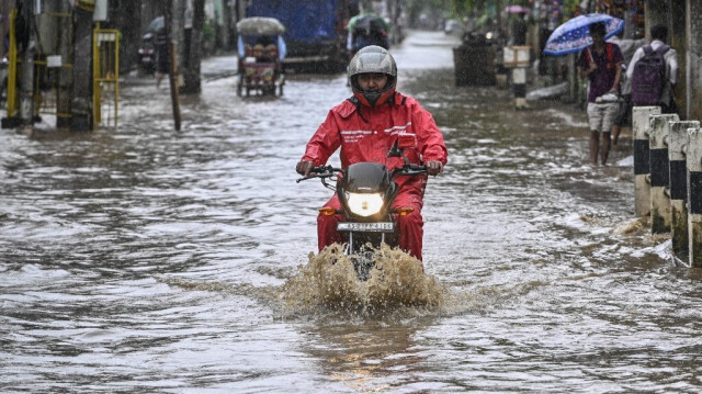 Un homme à moto se déplace dans une rue inondée après de fortes pluies pendant la mousson à Guwahati.