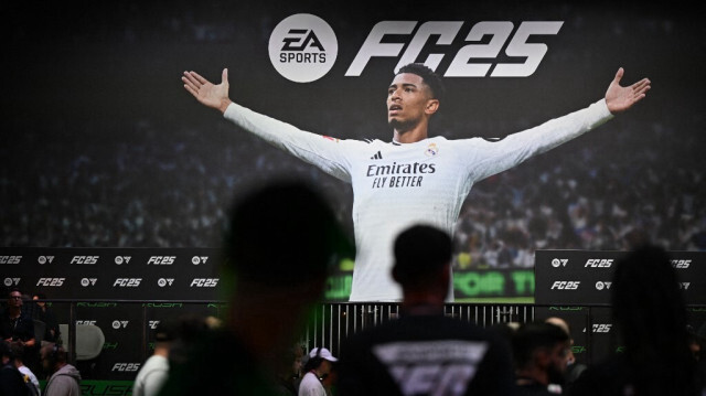 Des visiteurs jouent au jeu "EA Sports FC 25" devant une affiche représentant le milieu de terrain anglais Jude Bellingham sur le stand d'Electronic Arts lors de la journée des médias du salon des jeux vidéo Gamescom à Cologne, dans l'ouest de l'Allemagne, le 21 août 2024. 