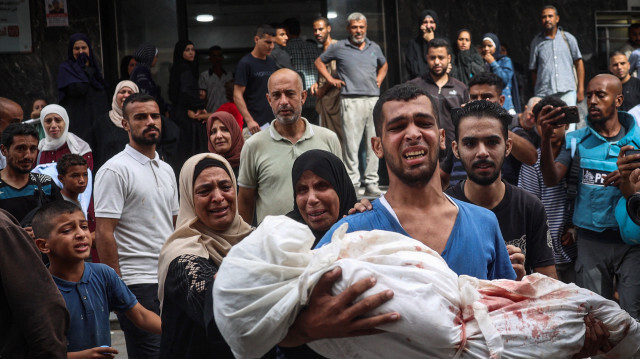 Un Palestinien porte le corps d'un enfant tué lors de frappes israéliennes sur le camp de réfugiés de Bureij, à l'hôpital al-Awda du camp de réfugiés de Nuseirat, dans le centre de la bande de Gaza, le 17 septembre 2024, alors que le conflit entre Israël et le groupe militant palestinien du Hamas se poursuit.