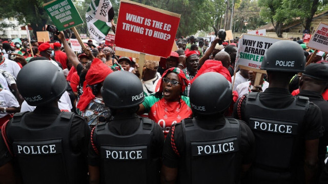 Un partisan du Congrès démocratique national (NDC) tient une pancarte devant des officiers de police lors d'une manifestation nationale du NDC contre l'inscription sur les listes électorales avant l'élection présidentielle de 2024 à Accra, le 17 septembre 2024.