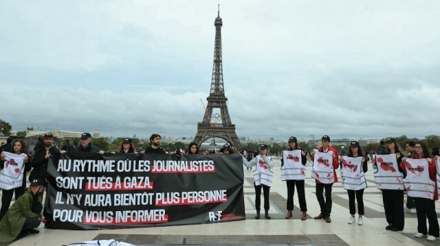 Des membres de Reporters sans frontières (RSF) tiennent une banderole et des gilets de presse tachés de faux sang lors d'une action organisée en soutien aux journalistes travaillant dans la bande de Gaza et en hommage à ceux qui ont été tués par Israël, au Trocadéro, à Paris, le 26 septembre 2024. 