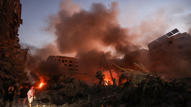 De la fumée s'élève des décombres fumants alors que des personnes se rassemblent sur les lieux des frappes aériennes israéliennes dans le quartier de Haret Hreik, dans la banlieue sud de Beyrouth, le 27 septembre 2024. Une source proche du Hezbollah a déclaré que les frappes israéliennes massives sur la banlieue sud de Beyrouth ont rasé six bâtiments.