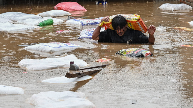 Un homme portant un sac de farine patauge dans les eaux de crue après le débordement de la rivière Bagmati à la suite de fortes pluies de mousson à Katmandou le 28 septembre 2024. Les inondations et les glissements de terrain provoqués par de fortes pluies au Népal ont tué au moins 10 personnes dans ce pays himalayen, et les équipes de secours sont à la recherche de 18 disparus, a déclaré un responsable de la gestion des catastrophes le 28 septembre.