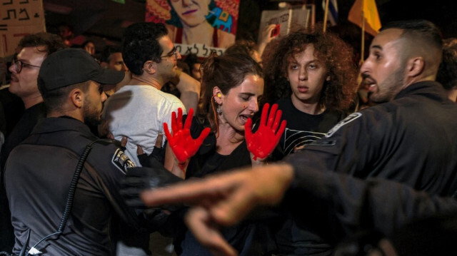 Des manifestants les mains peintes en rouge se battent avec la police israélienne près d'une barrière, non loin de la résidence du Premier ministre israélien à Jérusalem, le 2 septembre 2024.