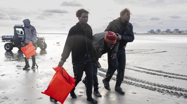 Un migrant aidé par deux autres lors d'une tentative de traversée de la Manche, sur la plage de Gravelines, près de Dunkerque, dans le nord de la France, le 26 avril 2024.