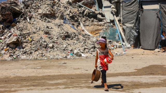 Une fille porte au milieu des décombres des bâtiments détruits lors d'un bombardement israélien, dans le camp de Jabalia, à Gaza, le 29 août 2024.