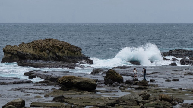 Des personnes prennent des photos devant de fortes vagues près du bord de mer dans le port de Badouzi à Keelung le 30 septembre 2024, en préparation du typhon Krathon.