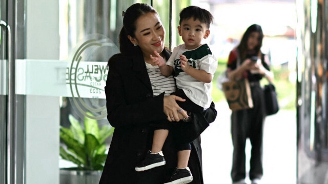 La Première ministre thaïlandaise Paetongtarn Shinawatra, connue sous le surnom de "Ung Ing" et fille de l'ancien Premier ministre Thaksin Shinawatra, pose avec son fils Thasin à son arrivée à la Tour Shinawatra à Bangkok, le 4 septembre 2024.