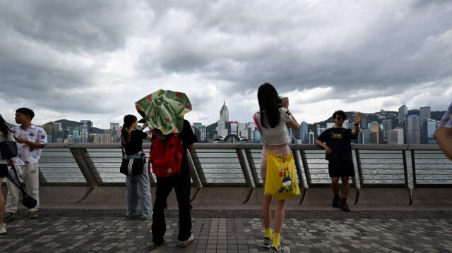 Des touristes prennent des photos sur la promenade du port de Victoria à Hong Kong le 5 septembre 2024, alors que le super typhon Yagi traverse la mer de Chine méridionale en direction de la côte sud de la Chine.