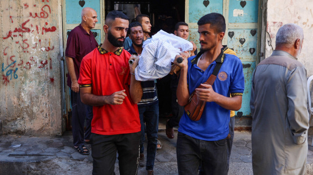 Des personnes portent le corps enveloppé d'un homme tué lors d'une frappe israélienne sur l'école Amr Ibn al Aas abritant des Palestiniens déplacés dans le quartier de Sheikh Radwan à Gaza City, le 7 septembre 2024, dans le cadre de la guerre en cours entre Israël et le groupe militant du Hamas.