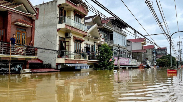 Des personnes se tiennent sur leur balcon au-dessus d'une rue inondée dans le district de Trang Dinh, province de Lang Son, le 9 septembre 2024, après que le typhon Yagi a balayé le nord du Viêt Nam.
