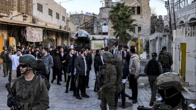 Des soldats de l'armée israélienne montent la garde alors que des colons juifs israéliens visitent le vieux marché de la ville d'Hébron, en Palestine occupée. 