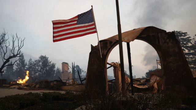 Un drapeau américain flotte au milieu des structures brûlées au Altadena Town & Country Club lors de l'incendie Eaton, le 8 janvier 2025 à Altadena, en Californie.