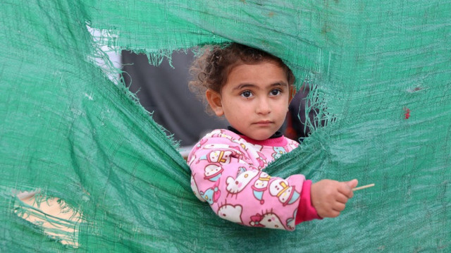 Une fille palestinienne se tient à l'extérieur de sa tente dans un camp de fortune pour les Palestiniens déplacés, pendant une tempête dans la ville de Gaza, le 31 décembre 2024.