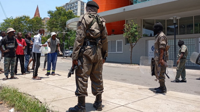 Des policiers mozambicains regardent les gens se rassembler pour manifester à Maputo le 15 janvier 2025, alors que Daniel Chapo prête serment pour être assermenté en tant que président du Mozambique lors de son investiture sur la place de l'Indépendance.