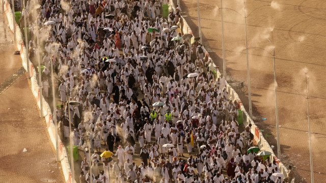 Des pèlerins musulmans marchent sous des brumisateurs alors qu'ils arrivent pour accomplir le rituel symbolique de la "lapidation de Satan" lors du hajj annuel à Mina, le 16 juin 2024.