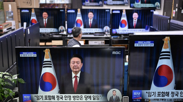 Des écrans de télévision montrent des images en direct d'un discours du président sud-coréen Yoon Suk Yeol, sur un marché électronique à Séoul, le 7 décembre 2024. 