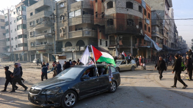 Des personnes circulent dans une voiture ornée d'un drapeau palestinien dans une rue de la ville de Gaza le 19 janvier 2025, à la suite de l'accord de cessez-le-feu.