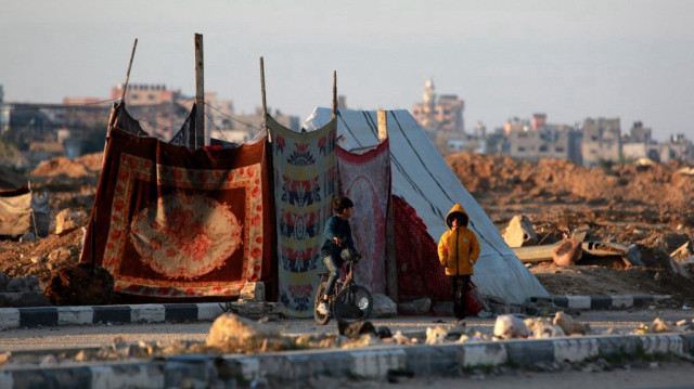 Des enfants palestiniens déplacés se tiennent devant leur tente au lever du soleil à Bureij, dans le centre de la bande de Gaza, le 19 janvier 2025.