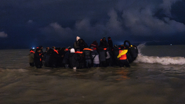 Des migrants montent à bord du canot pneumatique d'un passeur pour tenter de traverser la Manche, sur la plage de Blériot à Sangatte, près de Calais, dans le nord de la France, le 30 octobre 2024.