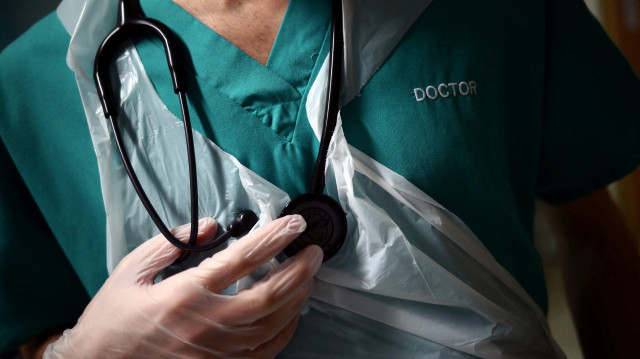 Un jeune médecin tient son stéthoscope pendant la visite d'un patient au pavillon C22 du Royal Blackburn Teaching Hospital à Blackburn, dans le nord-ouest de l'Angleterre, le 14 mai 2020.