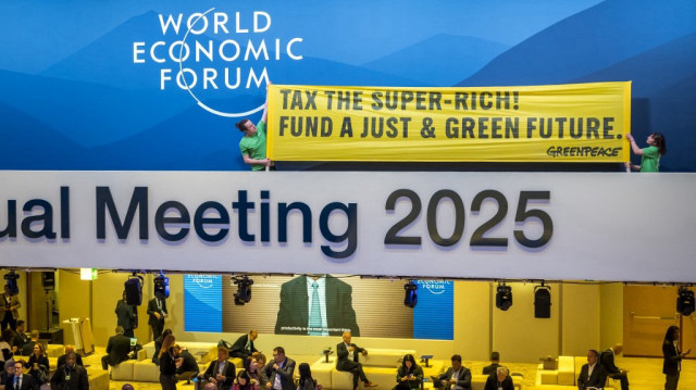 Des militants de Greenpeace tiennent une banderole lors d'une manifestation dans le hall principal du Centre des Congrès pendant la réunion annuelle du Forum économique mondial (WEF) à Davos, le 21 janvier 2025.  