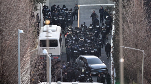 Des policiers pénètrent dans l'enceinte de la résidence présidentielle du président sud-coréen Yoon Suk Yeol à Séoul, vue d'une colline, le 15 janvier 2025.