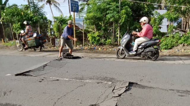 Des automobilistes roulant à vive allure sur une chaussée fissurée dans la ville de Liloan, dans la province de Leyte du Sud, après qu'un séisme de 5,8 ait frappé la province, le 23 janvier 2025.