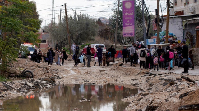 Des Palestiniens transportant leurs affaires empruntent une rue précédemment détruite par les forces israéliennes alors qu'elles fuient le camp de réfugiés de Jénine, en Palestine occupée, le 23 janvier 2025.