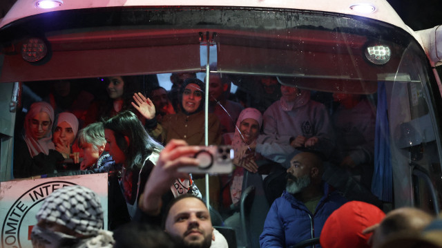 Des prisonniers palestiniens libérés de prison par Israël dans le cadre d'une trêve avec le Hamas à Gaza saluent la foule depuis l'intérieur d'un bus de la Croix-Rouge à leur arrivée aux premières heures du 20 janvier 2025 dans la ville de Beitunia, en Cisjordanie occupée, à la périphérie de Ramallah. La foule a applaudi, scandé et klaxonné lorsque deux bus transportant les prisonniers sont arrivés à Beitunia après leur libération dans le cadre de l'accord de cessez-le-feu à Gaza qui a débuté le 19 janvier et qui a vu la libération de trois otages israéliens par le Hamas dans la bande de Gaza.