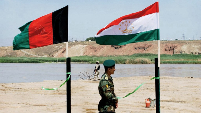 Un soldat de l'armée nationale afghane passe deavnt les drapeaux de l'Afghanistan et du Tadjikistan sur le port afghan de Shirkhan et Nizhny Pyandzh au Tadjikistan.