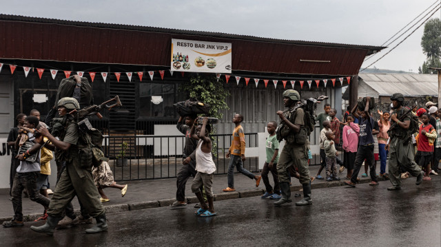 Des membres du groupe armé M23 marchent à côté de résidents dans une rue du quartier de Keshero à Goma, le 27 janvier 2025. 